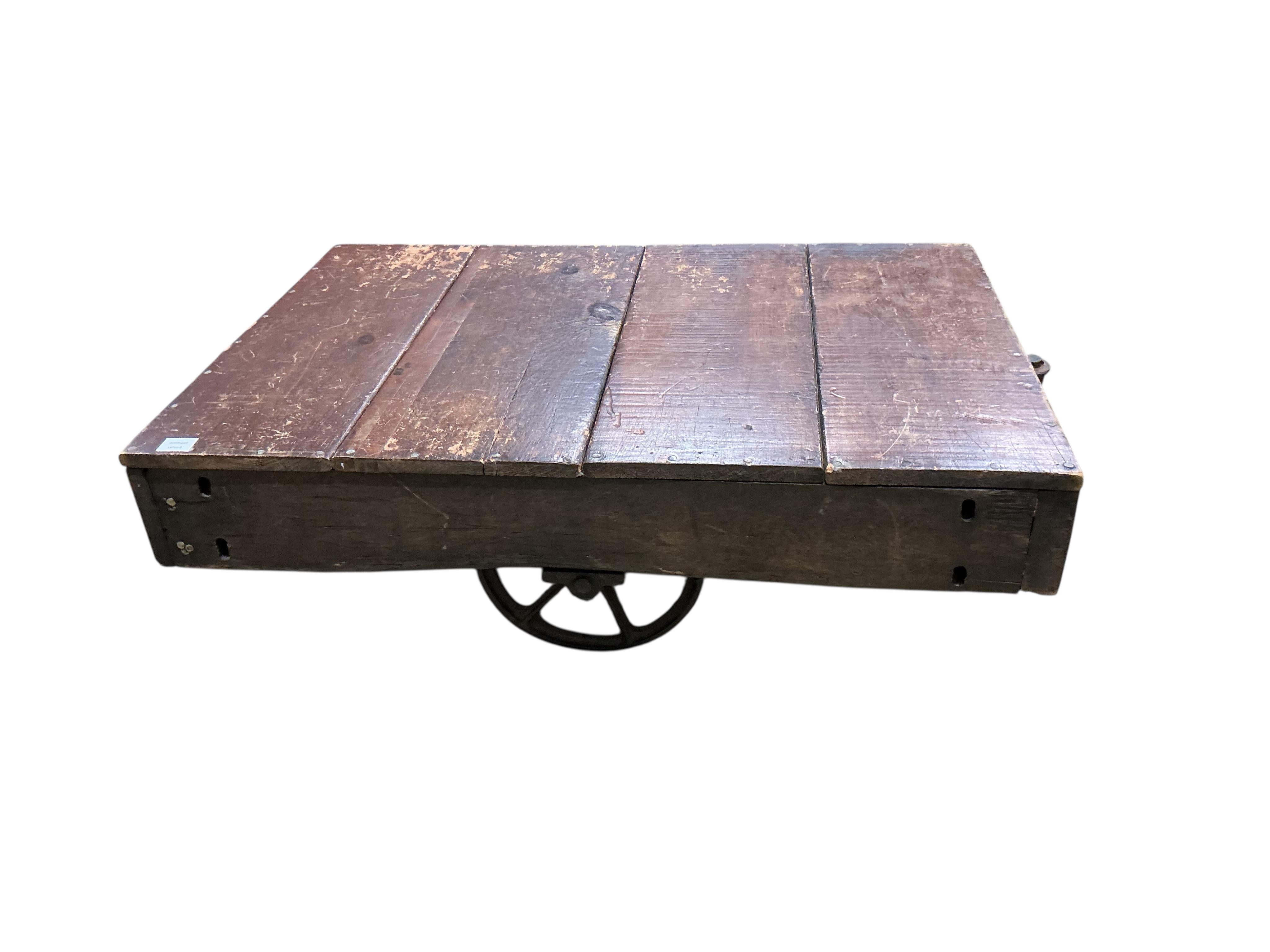 A vintage rectangular wood factory cart with iron spoked wheels now as a coffee table, width 112cm, depth 76cm, height 35cm